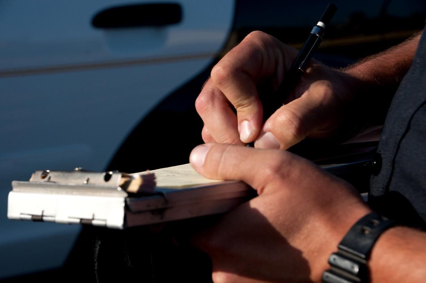 A police officer’s hands as he writes a traffic ticket.