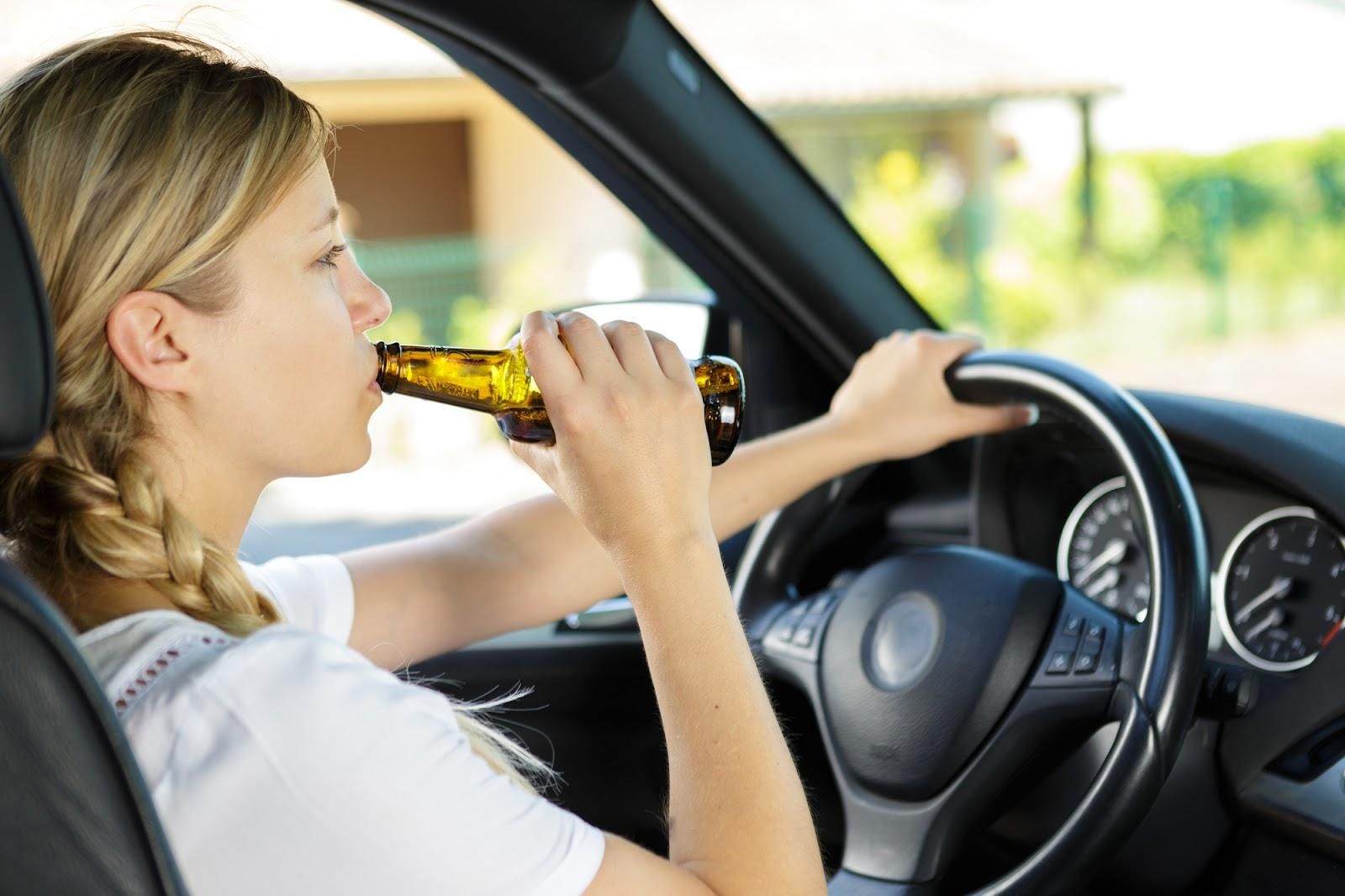 A teen in a car with a bottle of alcohol.