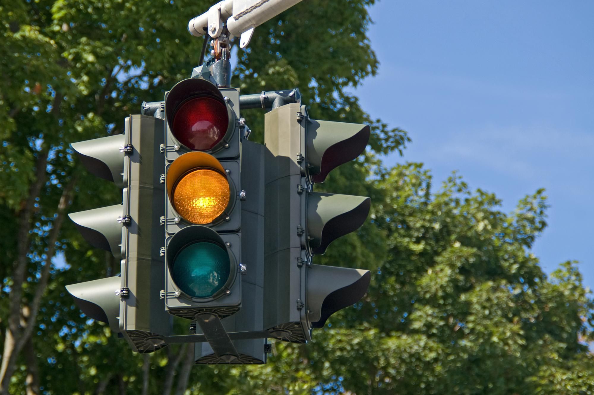 Closeup image of a traffic signal showing a steady yellow light.