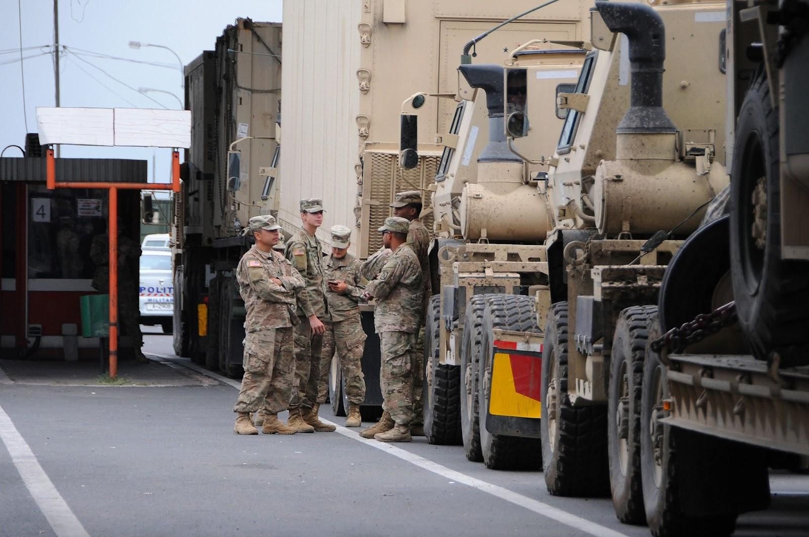 Military members discuss their license suspensions in front of vehicles.