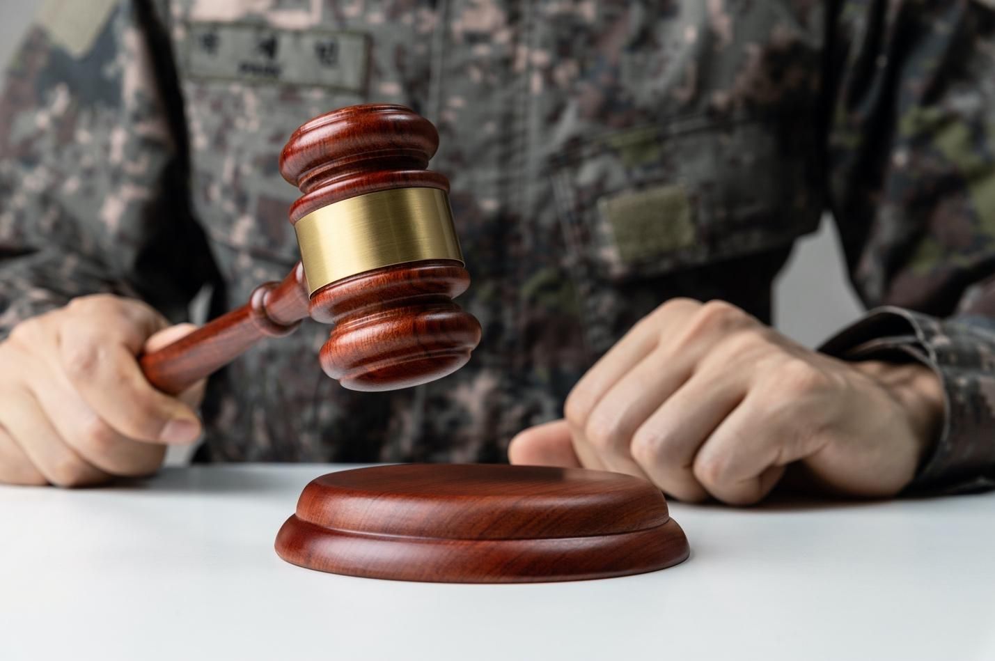 Military serviceman in fatigues tapping a judge’s gavel.