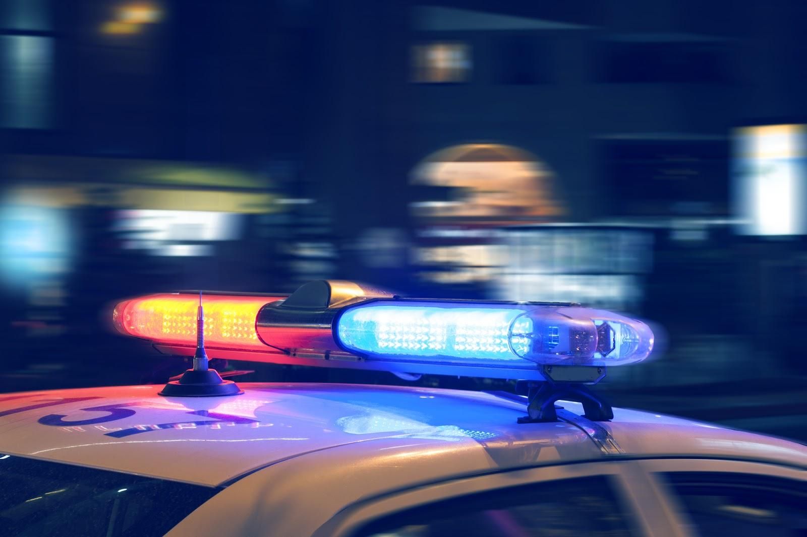 A police car at night, moving at a high speed, with its lights flashing.