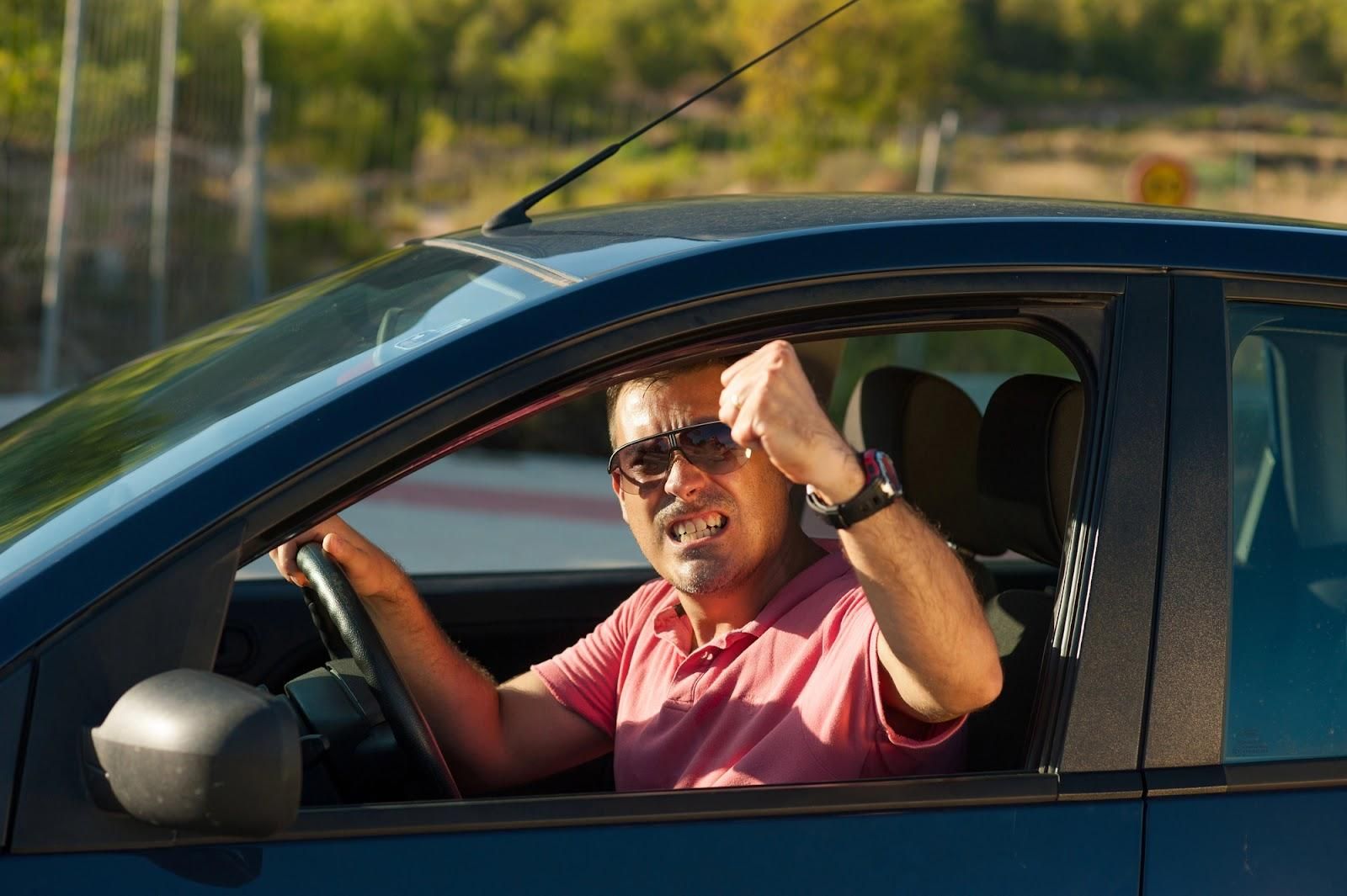 Angry driver shaking fist in traffic; road rage incident.