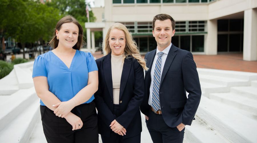 A man driving with city nightlife outside the windshield.